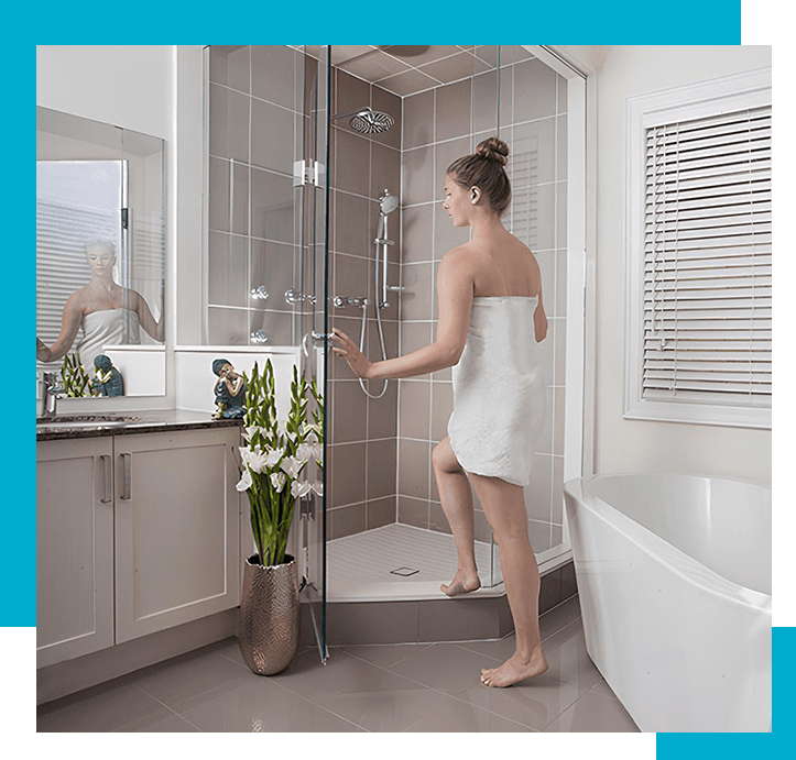 A woman in white towel standing on the edge of a shower.