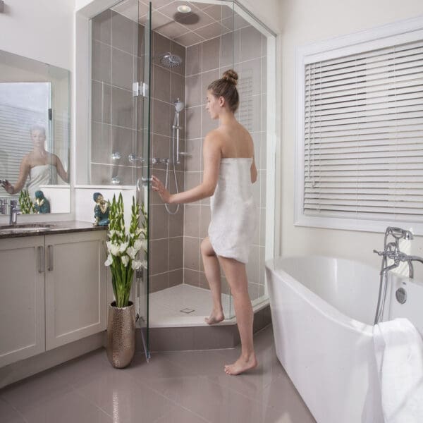 A woman in the bathroom standing next to a shower.